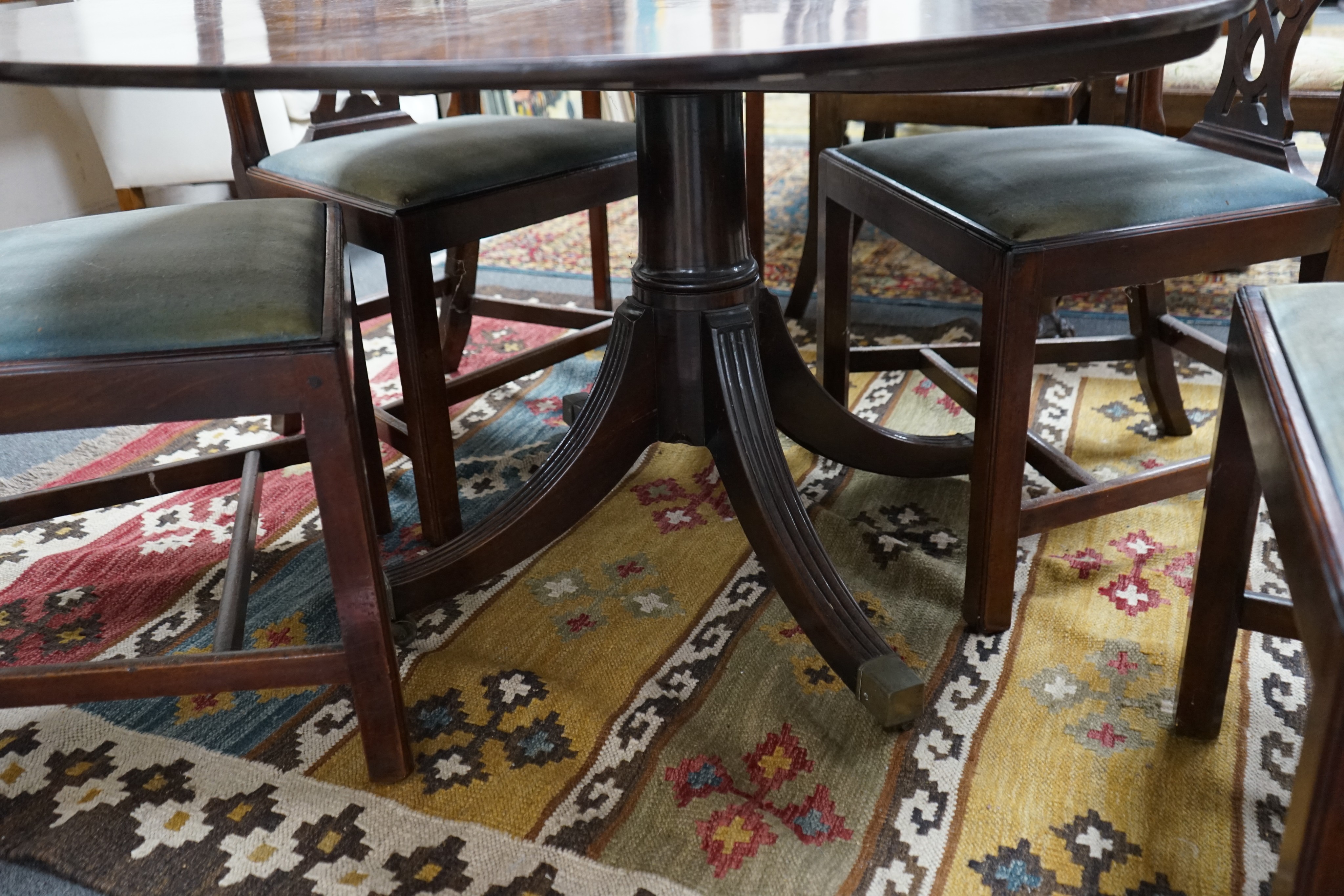 A George III oval mahogany tilt top dining table, altered, width 146cm, depth 106cm, height 69cm together with four George III mahogany dining chairs